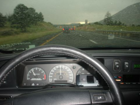 1990 Ford Taurus - View from the driver's seat on a rainy day, showing the dashboard and the road ahead with other vehicles.