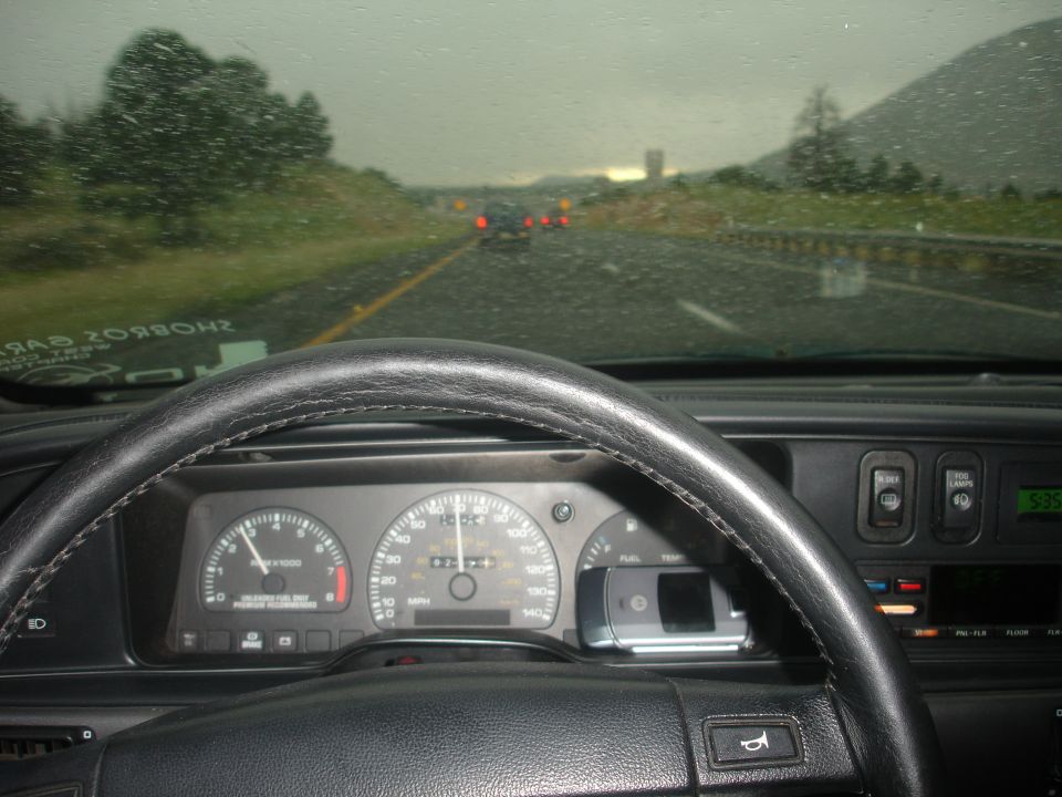SHO gauge cluster and steering wheel viewed from driver's seat on a rainy highway