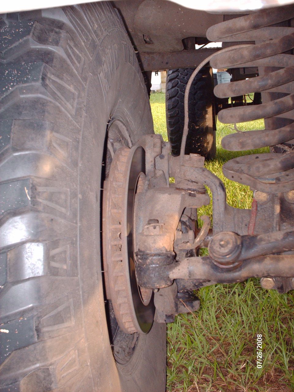 Close-up of a vehicle's front tire, brake rotor, and suspension system.
