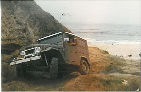 1991 Ford Bronco - Scanned vintage photo of a tan/primer-colored short-wheelbase 4x4 wagon with a white hardtop and round headlights, crawling at an angle dow…