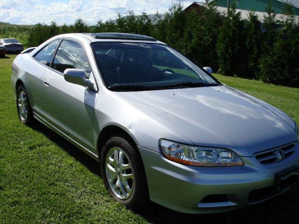 Silver 2002 Honda Accord coupe parked on grass, three-quarter front view.