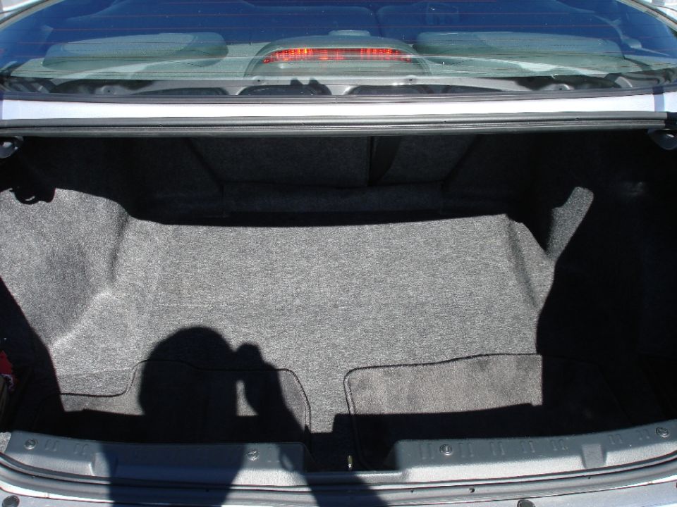 Open trunk of a silver sedan with dark gray carpet.