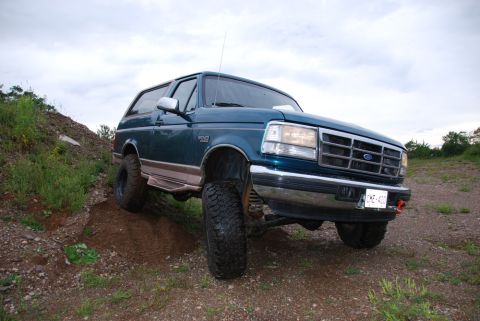 1996 Ford Bronco - Photograph of a lifted teal Ford Bronco posed on a dirt embankment, not a technical document.