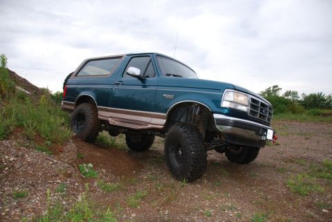 1996 Ford Bronco - Photograph of a lifted teal Ford Bronco on gravel terrain, not a technical document.