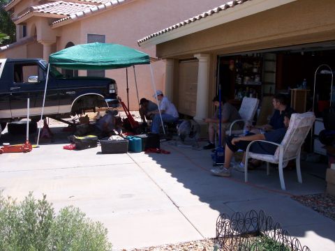 1996 Ford Bronco - A group of people are gathered around a lifted 1996 Ford Bronco that is under a green canopy. The vehicle is being worked on in a driveway…