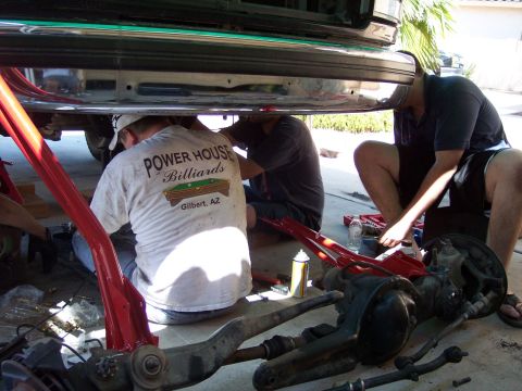 1996 Ford Bronco - Driveway axle swap in progress: a complete Dana-style front differential and axle assembly with knuckles and steering linkage lies on the c…