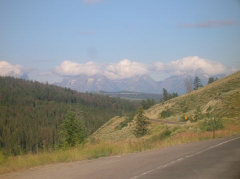 1996 Ford Bronco - A scenic view of mountains and a road cutting through a forested hillside under a partly cloudy sky.