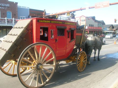 1996 Ford Bronco - A horse is harnessed to a vintage red stagecoach on a street with buildings in the background.