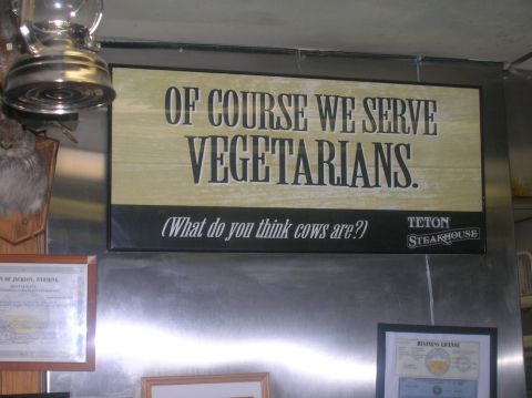 1996 Ford Bronco - A sign at Teton Steakhouse humorously states they serve vegetarians, questioning if cows are not.