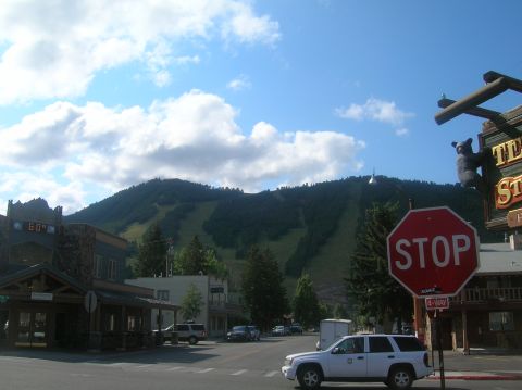 1996 Ford Bronco - A street scene in a mountain town, buildings, a stop sign, and several vehicles under a blue sky.