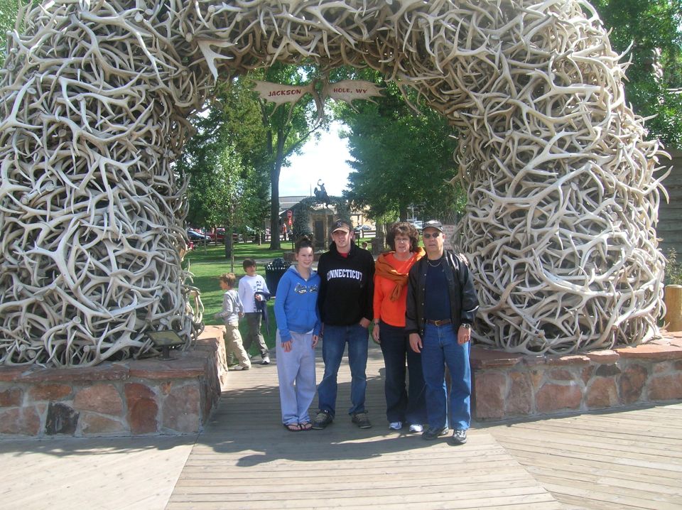 Family posing under a large archway made of antlers in Jackson Hole, WY