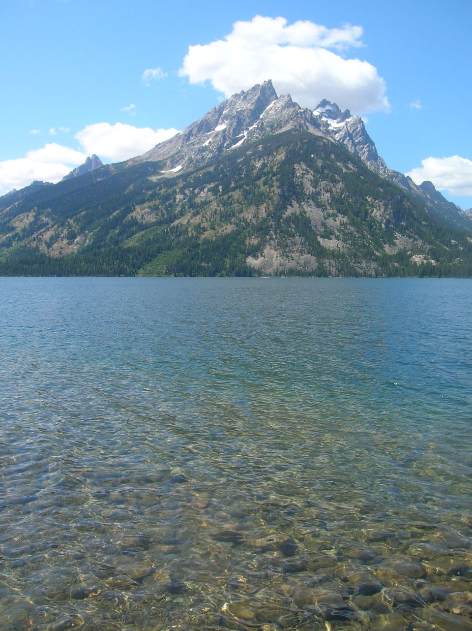 Mountain range reflected in a clear lake with rocky bottom