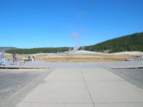 1996 Ford Bronco - Old Faithful erupts in Yellowstone National Park, with visitors observing from a boardwalk.