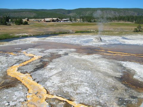 1996 Ford Bronco - A natural landscape geothermal activity, with a river and buildings visible in the distance under a clear sky.