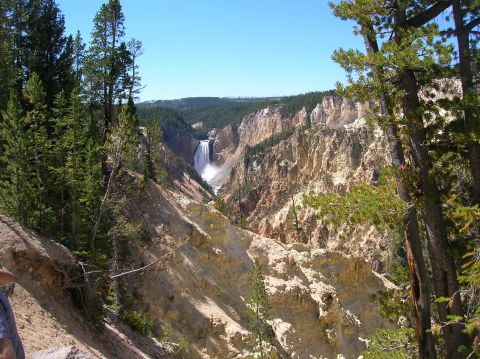 1996 Ford Bronco - A wide view of a canyon with a waterfall in the distance, surrounded by pine trees and rocky cliffs under a clear blue sky.