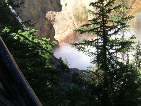 1996 Ford Bronco - A misty waterfall cascades down a canyon wall, framed by lush green pine trees and a wooden railing in the foreground.