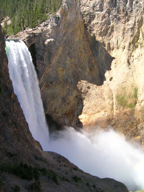 1996 Ford Bronco - A powerful waterfall cascades down a rocky canyon, creating a large cloud of mist at its base. Trees line the top of the canyon on the left…