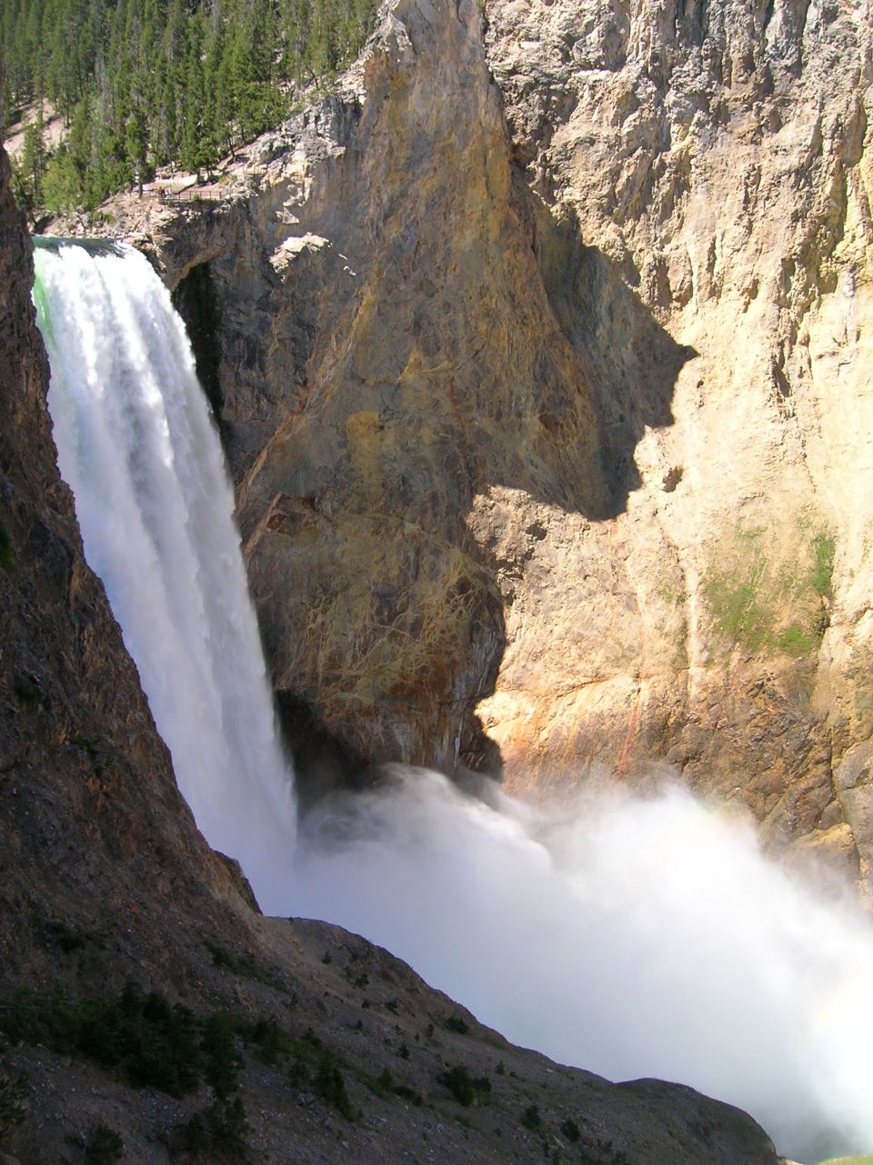 Waterfall in a rocky canyon with trees on top.