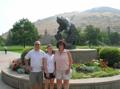 1996 Ford Bronco - A family of three poses for a photo in front of a bear statue on a sunny day. A large brick building with a clock tower is visible in the b…