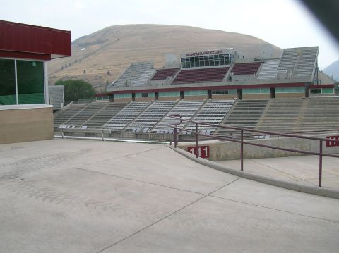1996 Ford Bronco - A view of an empty stadium with tiered seating and a large hill in the background. The stadium has "MONTANA GRIZZLIES" visible on a press b…