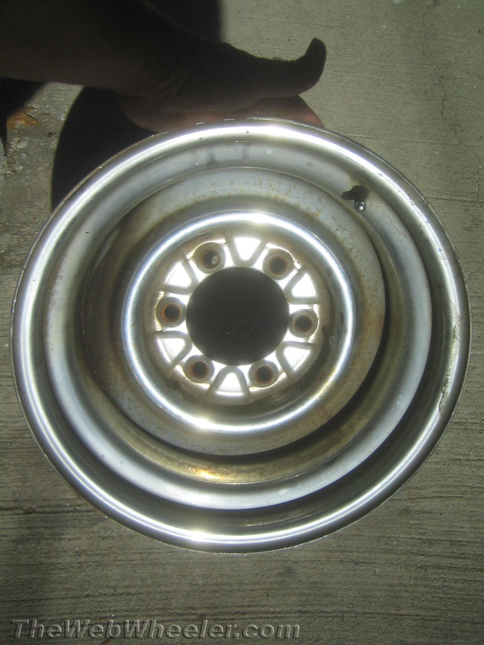 Steel truck wheel rim held up over concrete