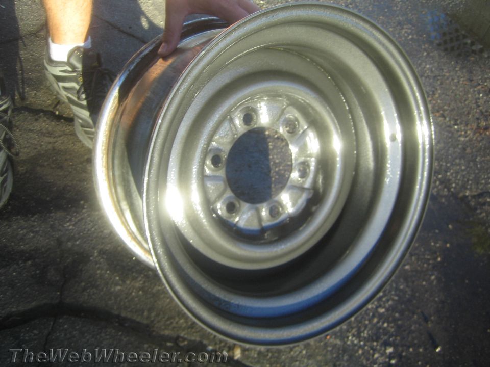 Polished steel wheel rim held up over pavement