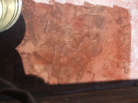 2005 Ford Mustang - A close-up view of a textured, reddish-brown surface with some water droplets, possibly a stamped concrete patio or walkway.