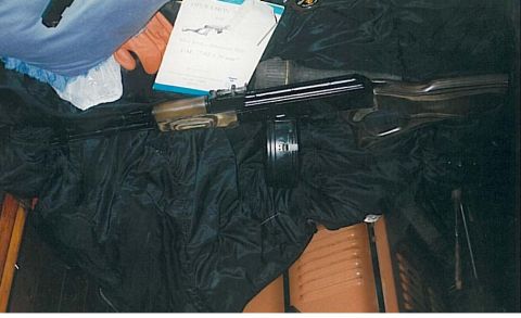 1991 Ford Bronco - A firearm with a drum magazine is laid out on a black cloth next to a document with text and an illustration of a firearm. The document app…