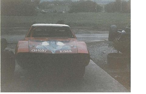 1991 Ford Bronco - The front of a red car with a white roof is shown, featuring a graphic design and the text "GHOST RIDER" on the hood. The vehicle is parked…