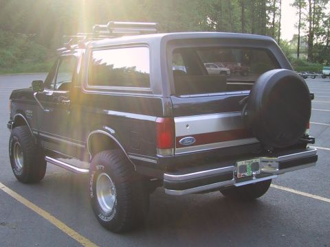 1989 Ford Bronco - Rear view of a black 1989 Ford Bronco with a roof rack and aftermarket wheels.
