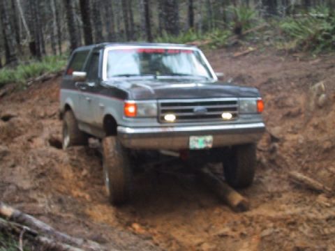 1989 Ford Bronco - This 1989 Ford Bronco navigates a challenging muddy path in a forest setting.