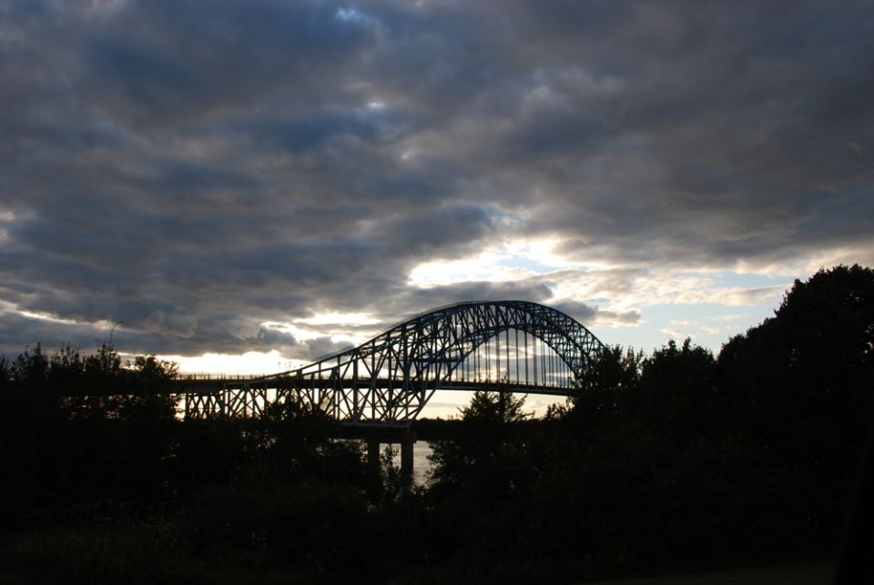 Silhouette of an arch bridge under a cloudy sunset sky