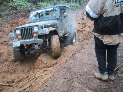 1989 Ford Bronco - A Jeep Wrangler navigates a challenging muddy off-road course.