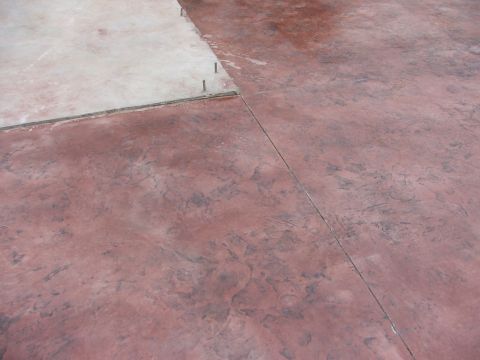 2005 Ford Mustang - A close-up view of a stamped concrete patio with a reddish-brown color and a lighter colored section in the upper left corner. The concrete…