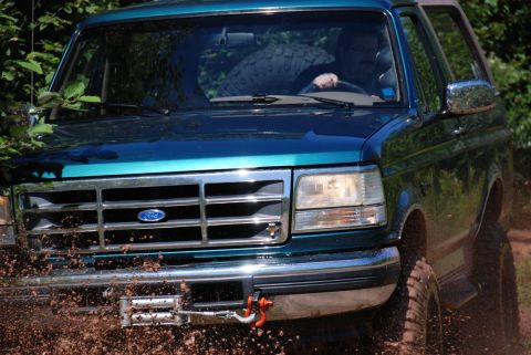 1996 Ford Bronco - Photograph of a teal Ford Bronco throwing mud off-road, not a technical document.