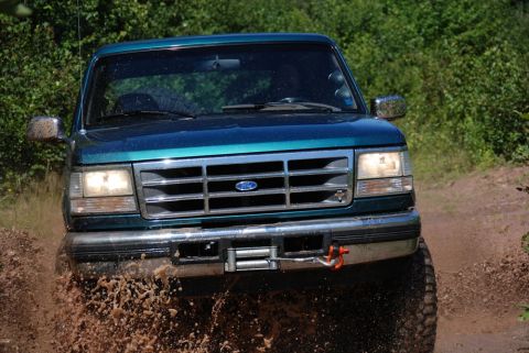 1996 Ford Bronco - Photograph of a teal Ford Bronco splashing through mud, not a technical document.