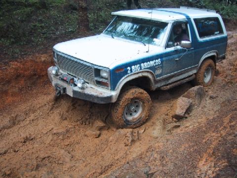 1989 Ford Bronco - Ford Bronco navigates a muddy trail, with '2 BIG BRONCOS' visible on the side.