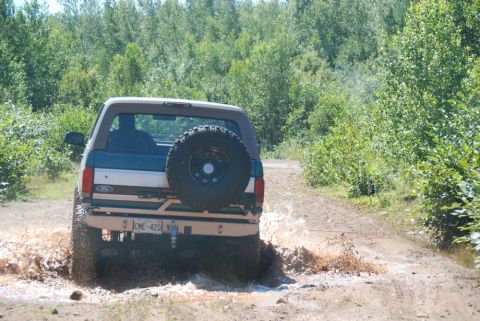 1996 Ford Bronco - Photograph of the rear of a teal Ford Bronco in mud, not a technical document.