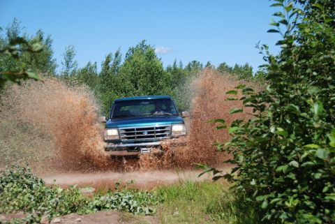 1996 Ford Bronco - Photograph of a blue Ford truck spraying mud on both sides, not a technical document.