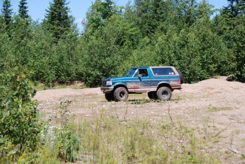 1996 Ford Bronco - Photograph of a teal Ford Bronco in a dirt clearing, not a technical document.