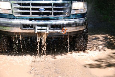 1996 Ford Bronco - Close-up photograph of a Ford truck front bumper and winch dripping mud, not a technical document.