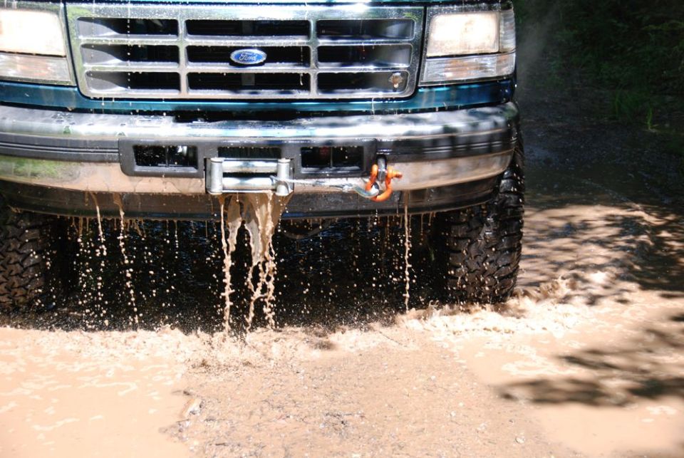 Close-up of Ford grille and winch dripping muddy water
