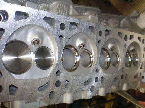 2007 Ford Mustang - Photograph of an aluminum cylinder head with machined chambers and valve seats, not a technical document.