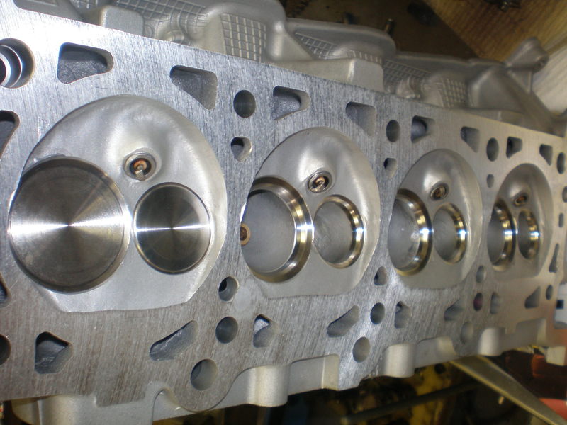Photo of a cylinder head deck showing several machined combustion chambers