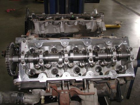 2007 Ford Mustang - Photograph of an assembled cylinder head with camshaft and timing sprocket on an engine, not a technical document.