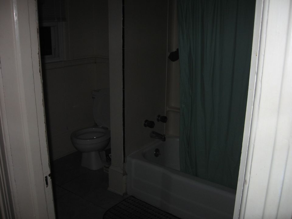 Dimly lit bathroom with toilet and bathtub