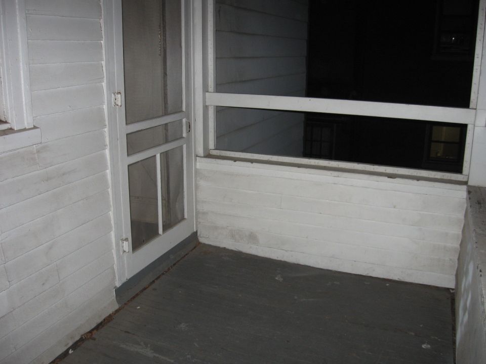 Screened-in porch with white wood siding and a screen door