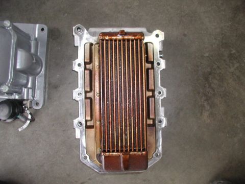 2007 Ford Mustang - A supercharger intercooler heat exchanger removed from an intake manifold, lying face-up on a concrete floor with its copper core discolore…