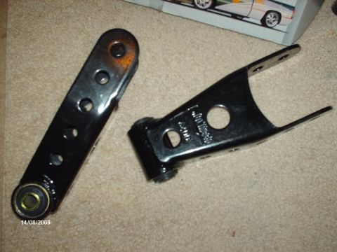 1990 Ford F-150 - Two black metal suspension components are shown on a carpeted surface, with text visible on one part.