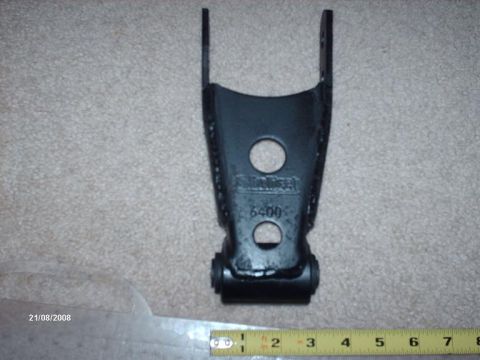 1990 Ford F-150 - A black leaf spring shackle, identified by the visible part number 6400, is shown against a carpeted background.